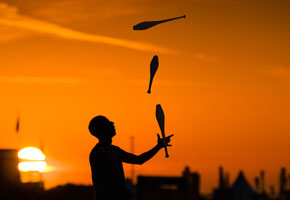 A juggler with 4 clubs at sunset