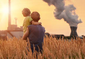 Father with son looking on chemical plant emissions at sunset time