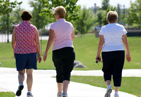 Three older women take a healthy walk through the park