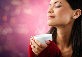 a woman enjoys the aroma of a cup of coffee