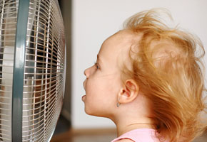 A little girl standing in front of fan