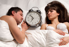 a couple sleeping with their alarm clock