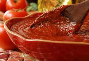 Freshly prepared pasta or pizza sauce in bowl with wooden spoon