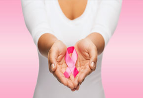 woman's torso in white tshirt holding a pink ribbon for beast cancer