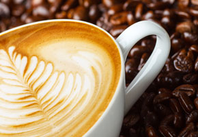 cup of pumpkin spice cafe au lait on a background of coffee beans