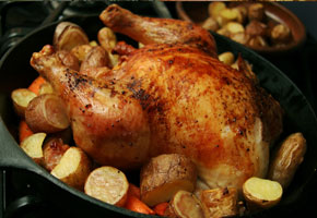 whole roasted chicken in a cast iron skillet surrounded by roasted potatoes
