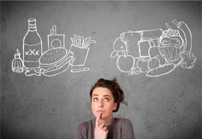 pretty woman standing in front of a chalk board, deciding between fast food and healthy food images