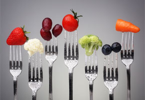 7 forks, each with a single vegetable or piece of fruit on the tines, against a silver background