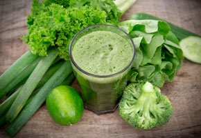 green vegetable smoothie on a wooden background with celery, cucumber and broccoli