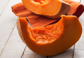 Halved and seeded pumpkin slices on a wooden background