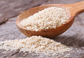 sesame seeds in a wooden spoon and on a tabletop