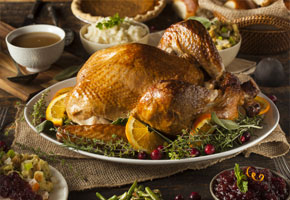 Thanksgiving roast turkey, on a platter surrounded by apples and oranges, on a harvest table