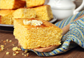a piece of cornbread, topped with butter, on a wooden table