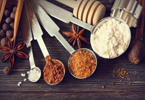 measuring spoons filled with spices on a wooden background with anise stars all around