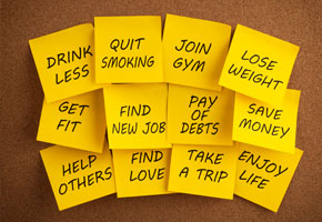 yellow post it notes stuck to a wooden background, each list a possible new years resolute ike lose weight, quit smoking or go to the gym more.