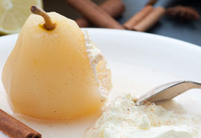 a poached pear on a white plate with coconut whipped cream