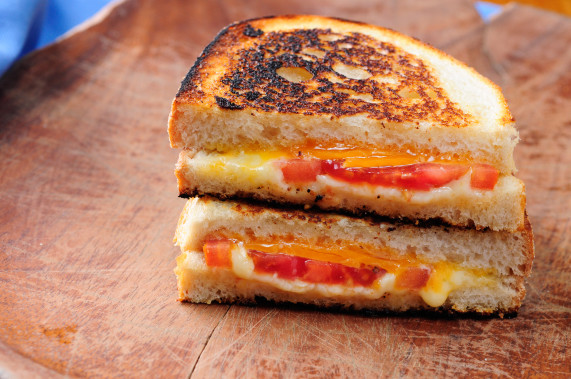 classic grilled cheese and tomato sandwiches on a wooden platter