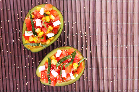 Tasty salad in avocado on bamboo napkin close-up