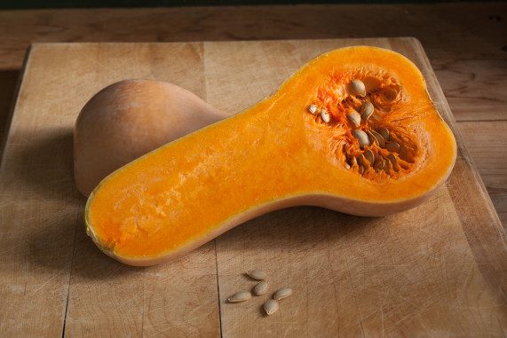 A sliced butternut squash with seeds on a cutting board.
